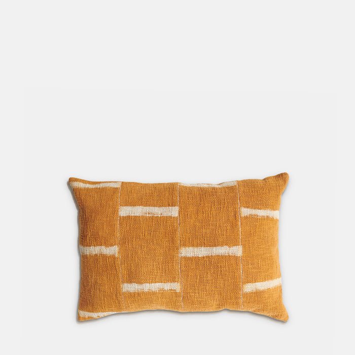 Cutout image on a white background of a rectangular cushion with a linear brick type pattern in orange and cream.