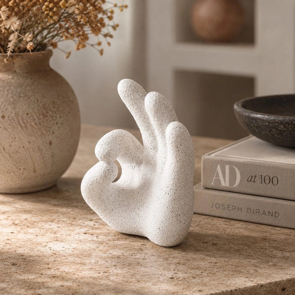 Ballo Hand Sculpture styled on a low table, its pale hand-shaped form surrounded by stacked books, dark seating and layered contemporary accessories.