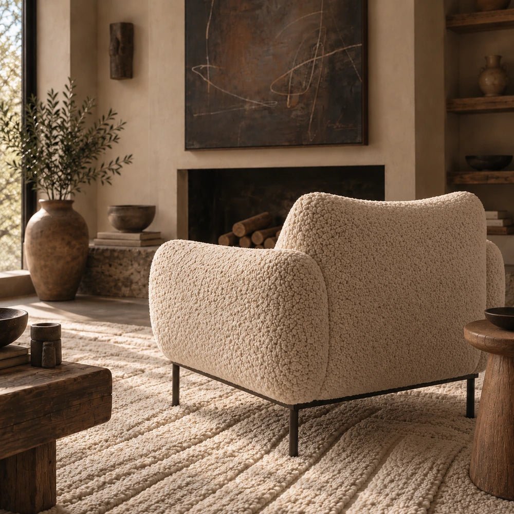 Belville Armchair in soft cream upholstery, styled in a warm contemporary room with layered neutral textures, sculptural furniture and decorative accessories.