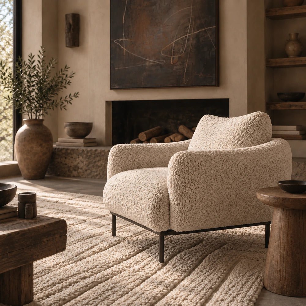 Belville Armchair in soft cream upholstery, styled beside neutral furnishings with layered cushions, warm textures and contemporary decorative accessories.