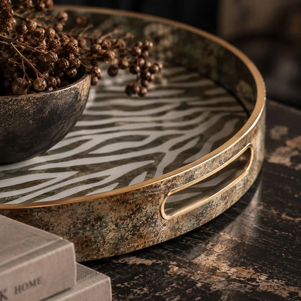 Bosso decorative tray shown close up, highlighting its gold toned oval handle, mottled metallic rim and zebra patterned base beneath a decorative bowl.