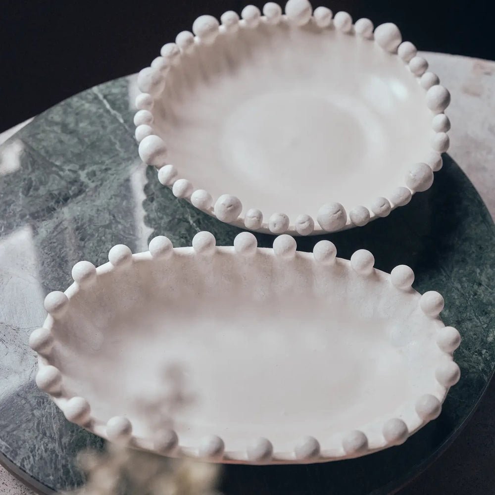 Brewster Bobble Bowl with an off-white glossy interior and rounded beaded edge, shown alongside a matching bowl on a dark circular display tray.