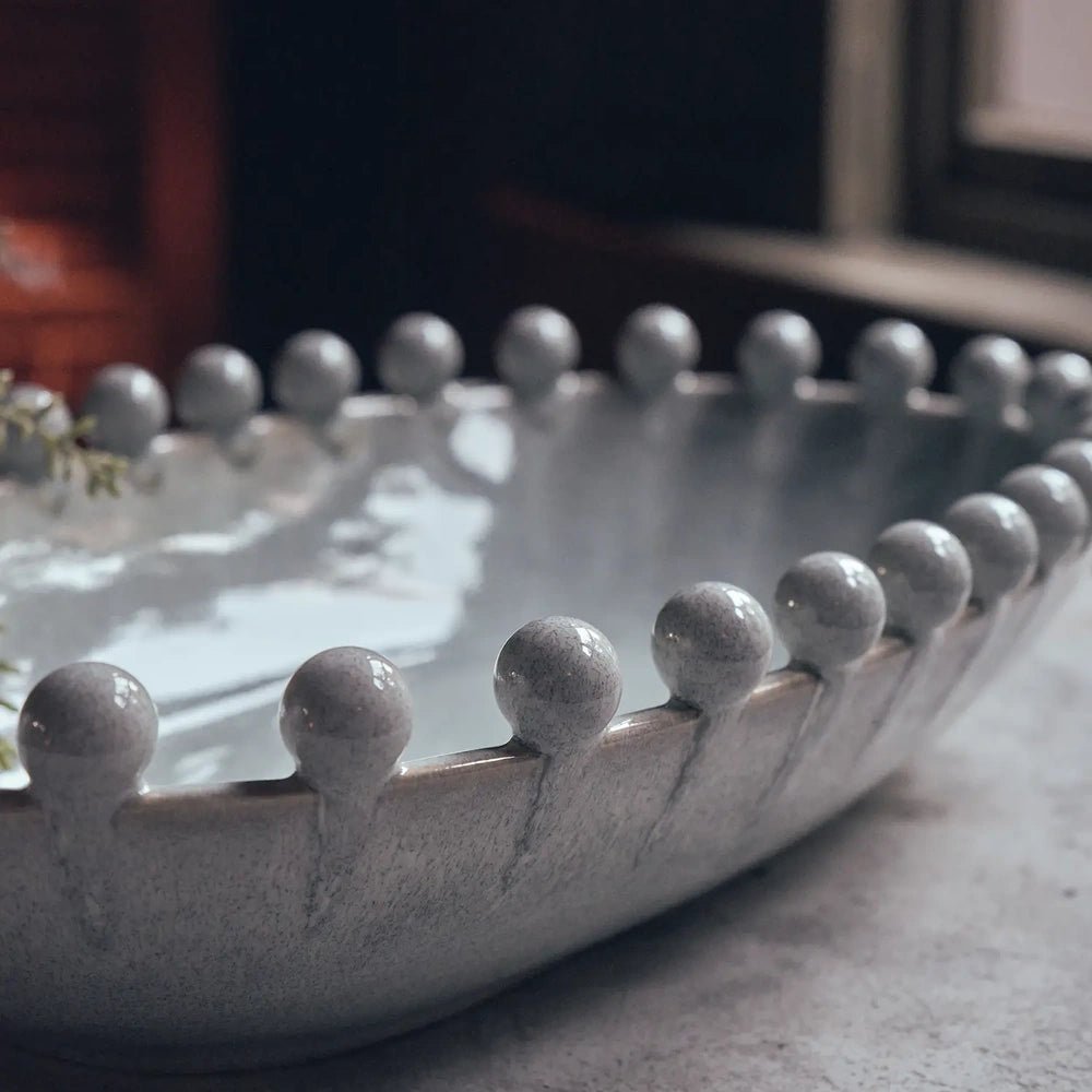 Brigham Bobble Decorative Bowl showing its glossy grey interior and rounded beaded rim, with reflected window light highlighting the shallow curved shape.