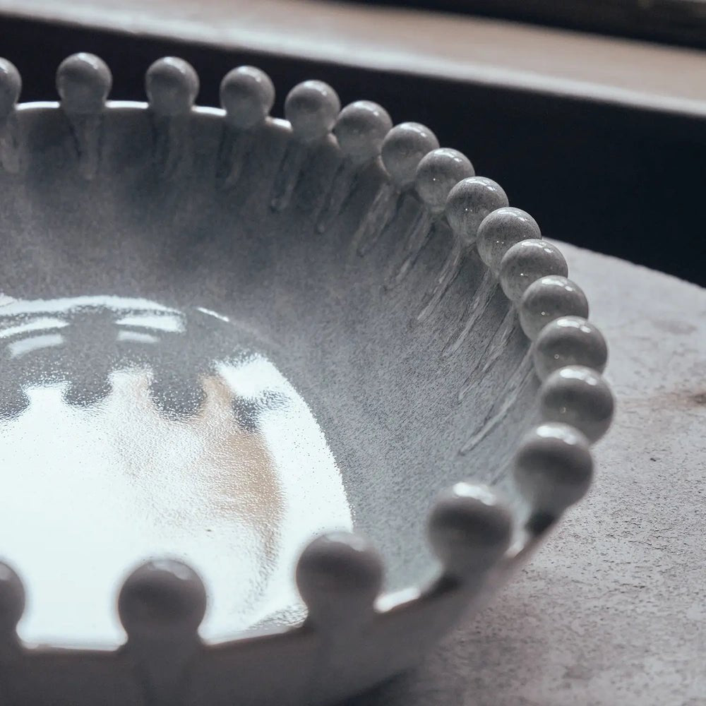 Brigham Bobble Decorative Bowl showing a shallow glossy grey interior and rounded beads around its rim, with soft window reflections across the glaze.