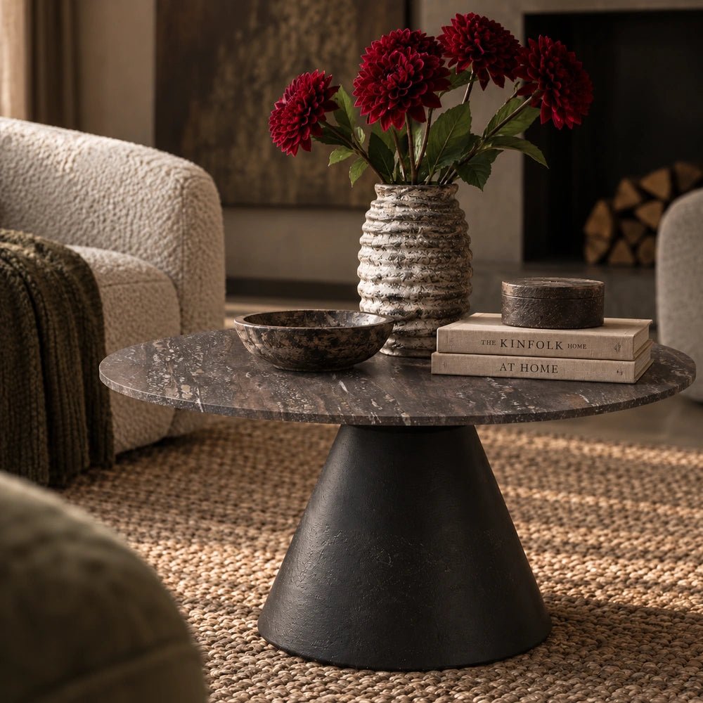 Burley Travertine Coffee Table in charcoal with textured stone appearance, styled before a neutral sofa with warm contemporary accessories and layered furnishings.
