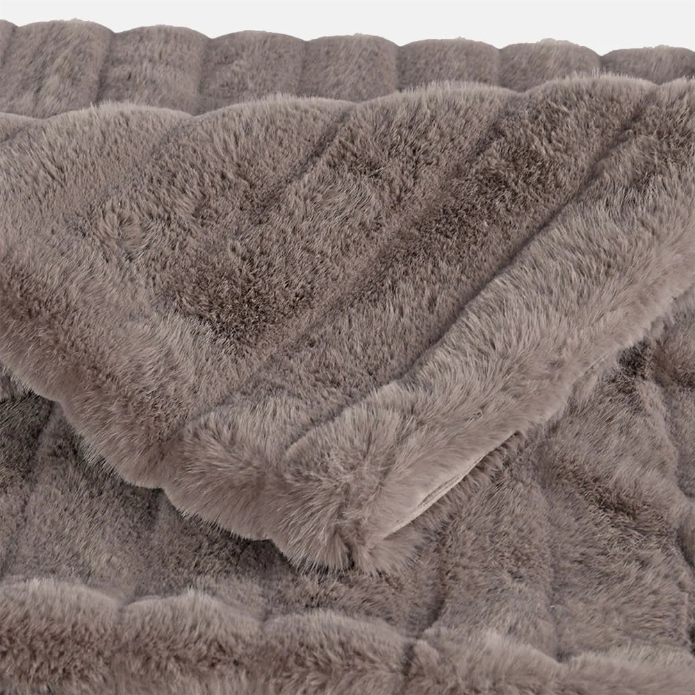 Chandler faux fur throw shown in close up, revealing a soft taupe surface, dense fluffy pile and wide raised ribs folding across the fabric.