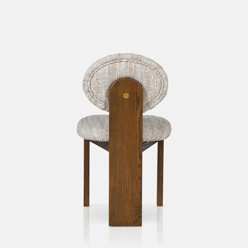 Channing boucle dining chair viewed from behind, showing its round cream upholstered backrest, broad wooden centre support, padded seat and warm brown wooden legs.