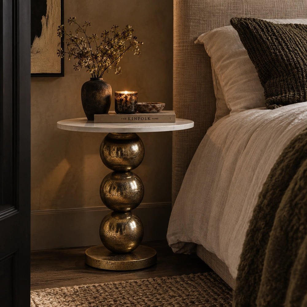 Chelsea Marble Side Table with round marble top and sculptural pedestal, styled between neutral seating with books, glassware and decorative objects.