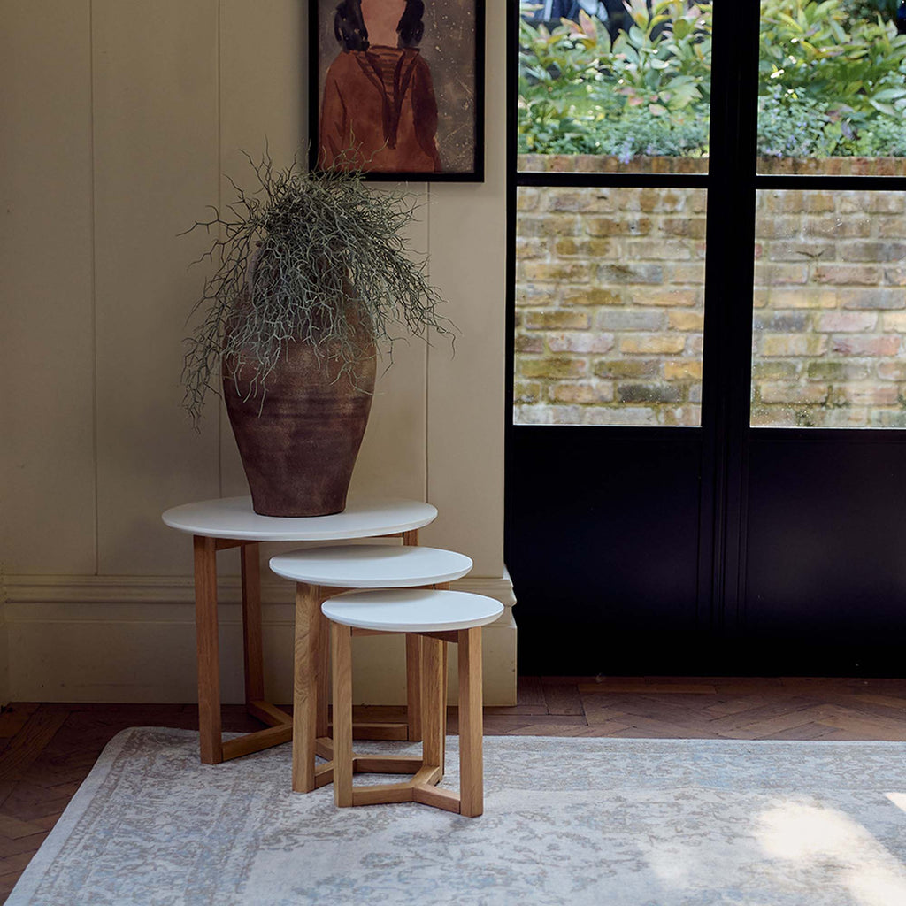 The Cutler White Side Tables - Set of 3, a set of circular nesting tables with a smooth white matte surface and oak wood legs.