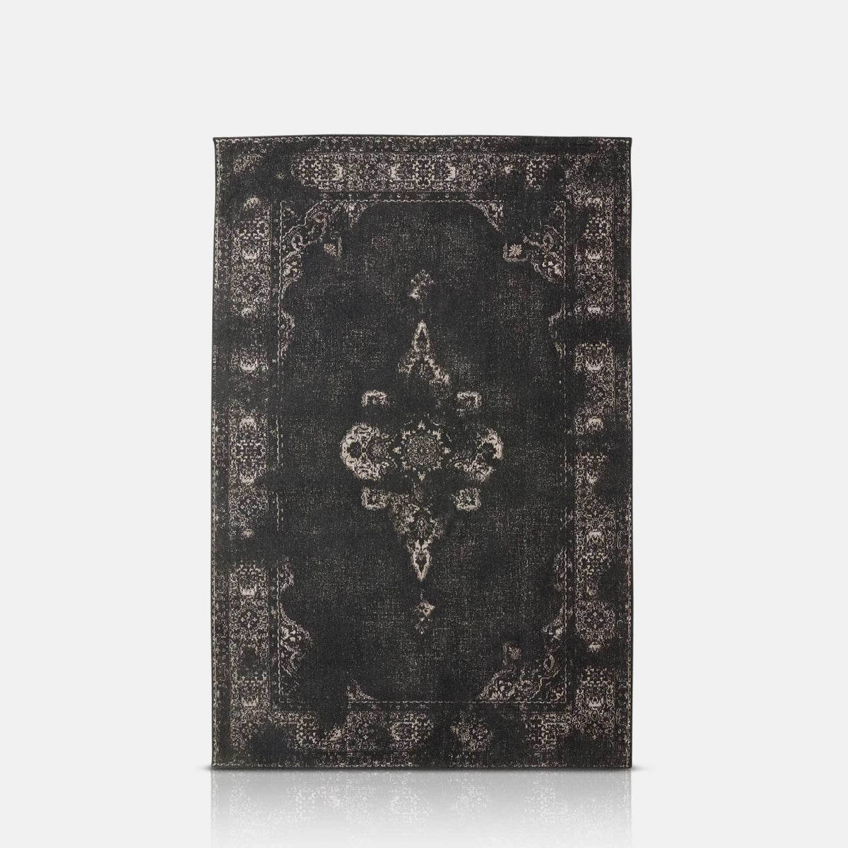 A cutout of the Dallam Woven Rug, a rectangular rug in a rich inky hue featuring an intricate antique pattern in white relief.