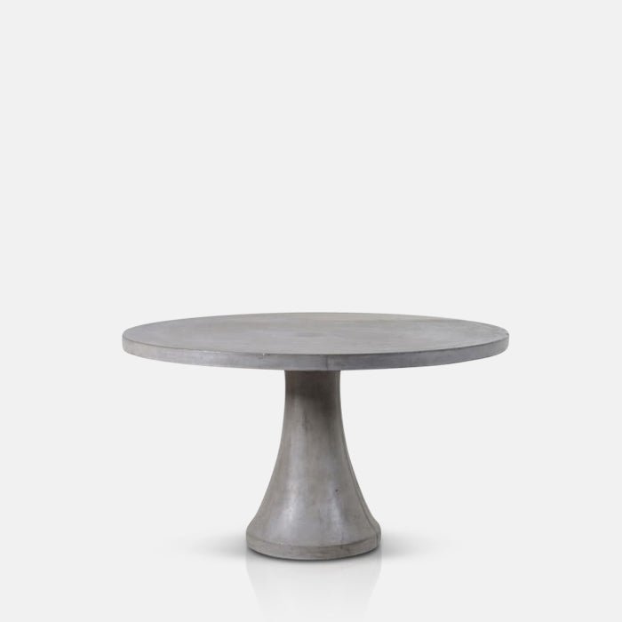 A cutout of the Datura Round Dining Table, a large round cement table with a pedestal base.