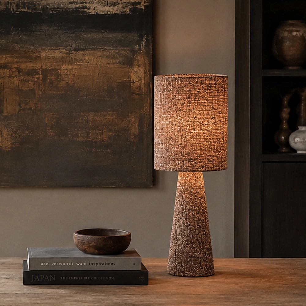 Draycott Boucle Table Lamp with textured boucle shade and sculptural base, glowing warmly on a bedside table in a softly styled neutral bedroom.