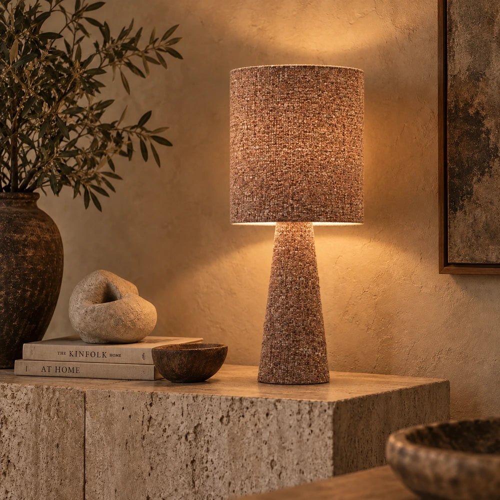 Draycott Boucle Table Lamp with tactile boucle shade and sculptural base, styled on a wooden table beside books and ceramics in a moody living room.