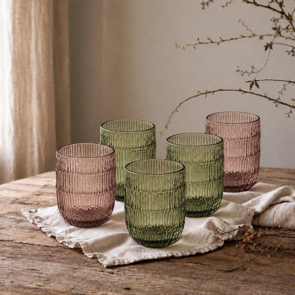 Elden Glass Cup, Green with ribbed translucent glass texture, grouped with blush and green tumblers on a rustic wooden dining table with neutral linen.