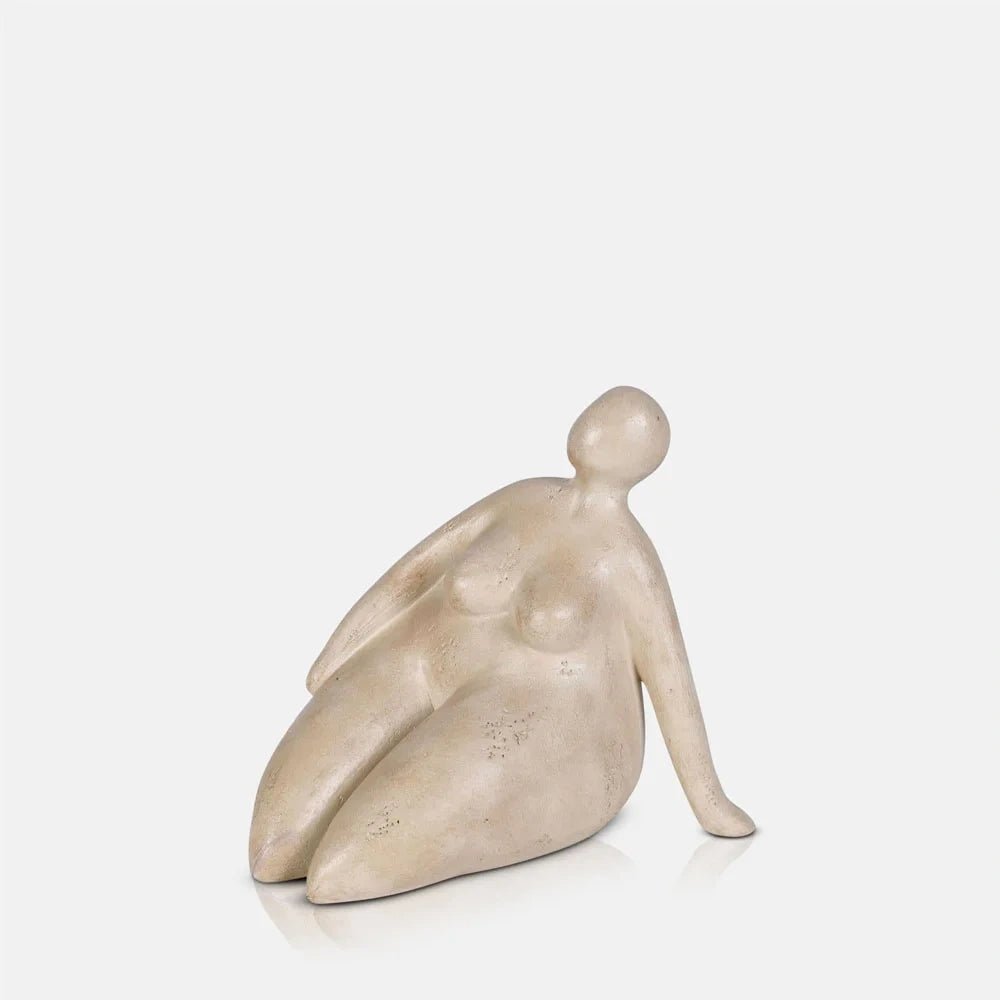 Ellery Figurative Sculpture depicts a seated figure with bent legs, a rounded head and smooth neutral finish, leaning back on one extended arm.