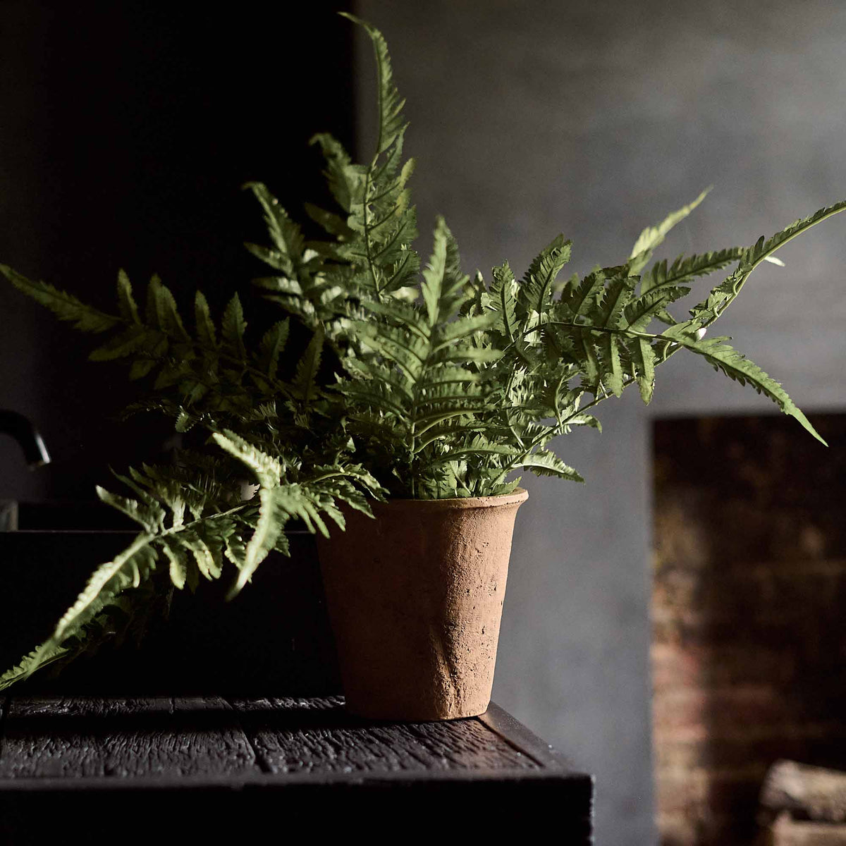The Artificial Fern in Terracotta Pot, a mid-sized faux fern with tall green fronds in a small brown terracotta pot.