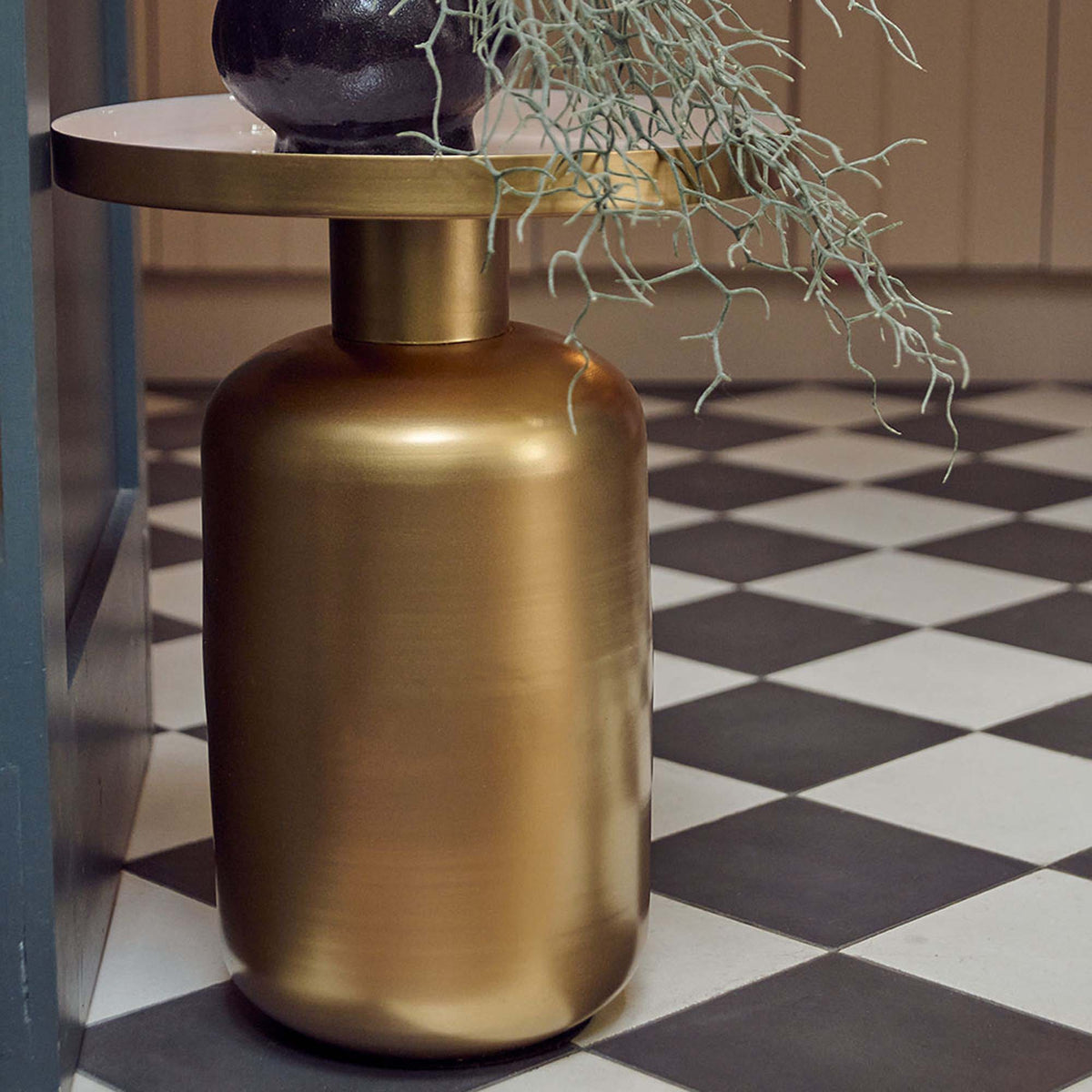 The Giles Gold Side Table, a round table with a wide curved cylindrical base in gold effetc and a white enamel tray style top.