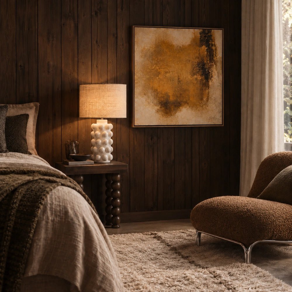 Greenock Bobble Table Lamp with rounded sculptural base and neutral shade, positioned on a console with books, ceramics and decorative styling in a dark interior.