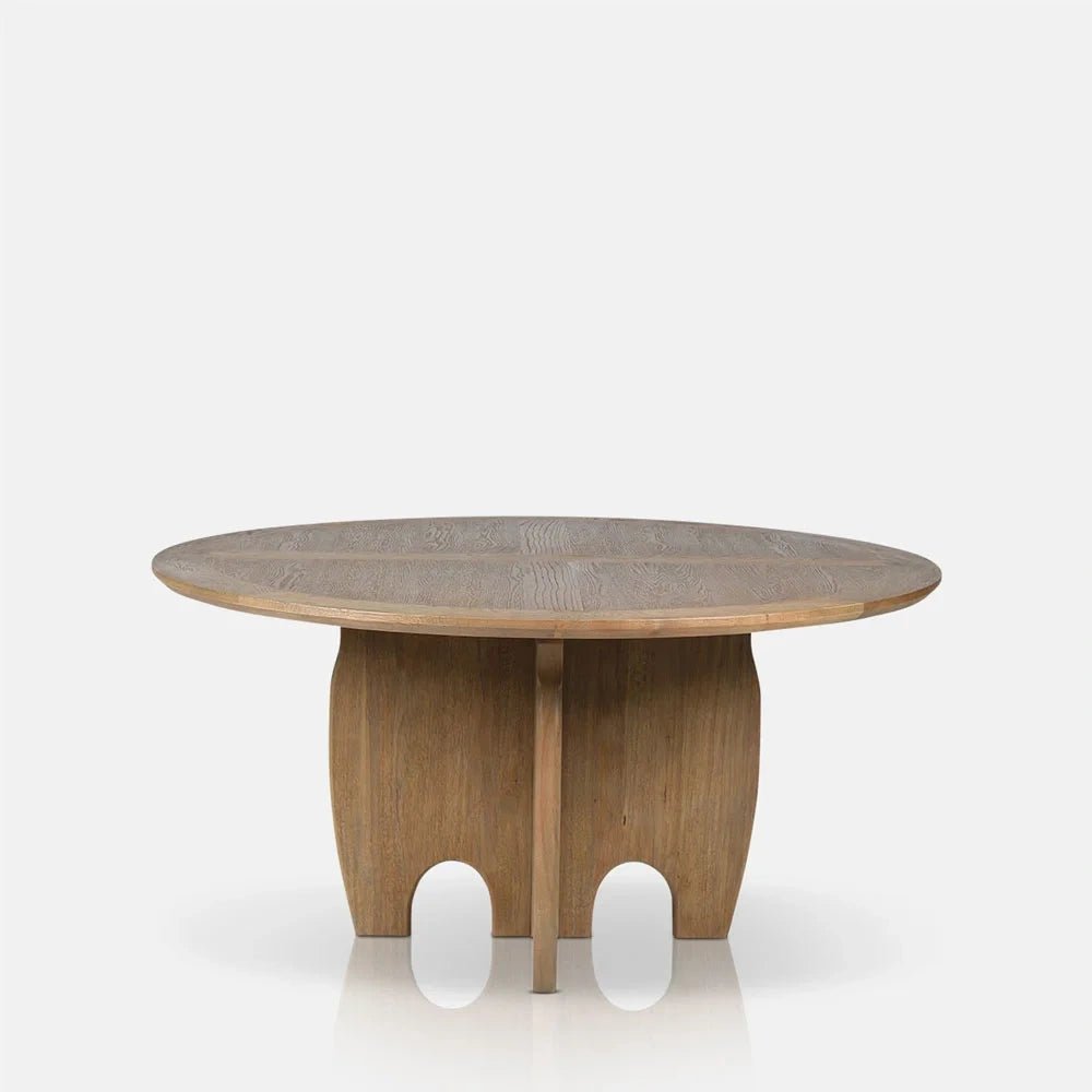 Harrington Wooden Dining Table features a round natural wood top above a sculptural pedestal with curved lower openings, shown in a straight front view.