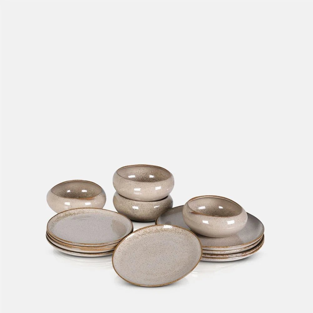 Hollister dinner set combines rounded taupe bowls and plates in coordinated sizes, with glossy speckled glazing and softly irregular rims across the grouped pieces.