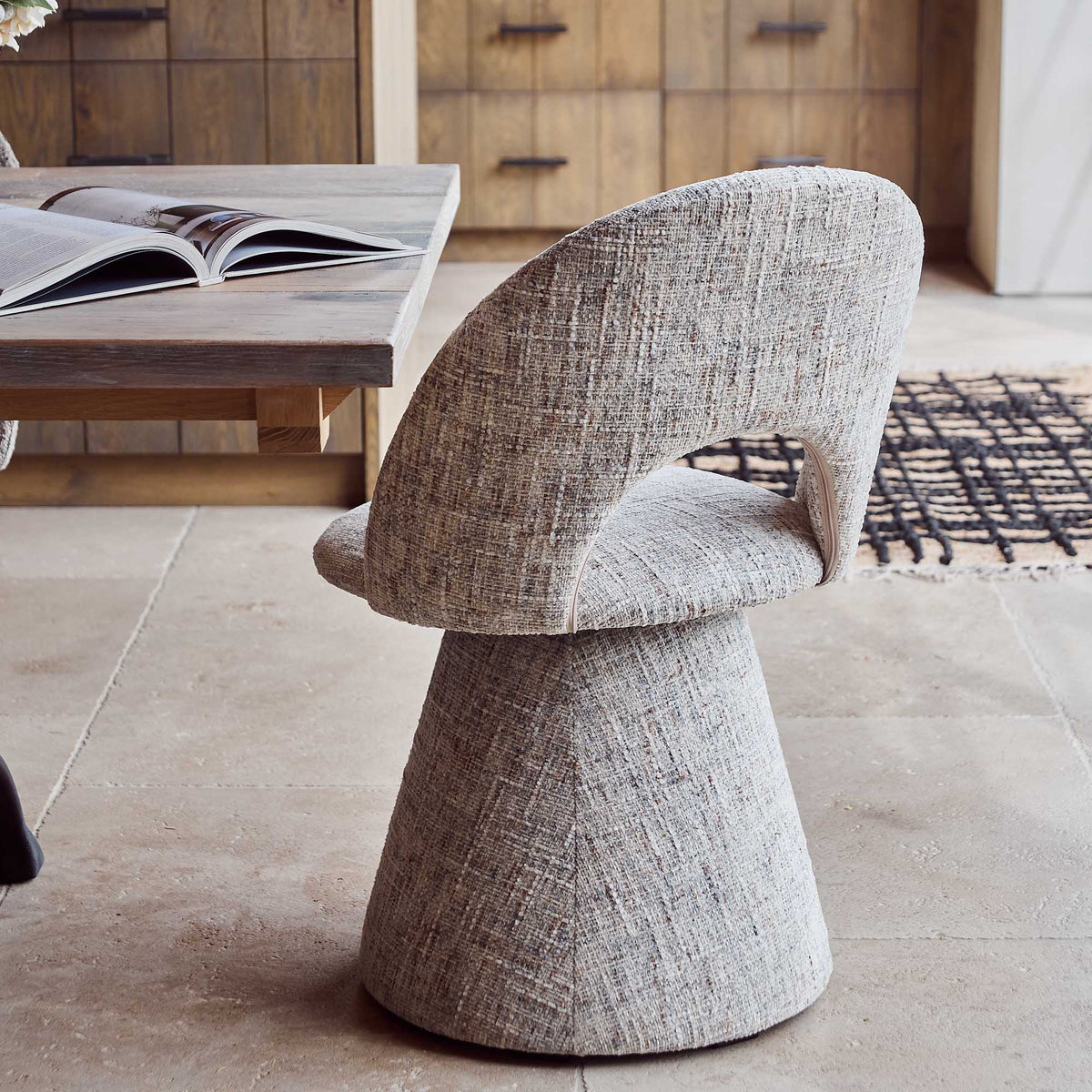 Contemporary upholstered, comfortable dining chair in a textured grey fabric featuring a sculptural curved silhouette a modern but organic design for stylish dining interiors.