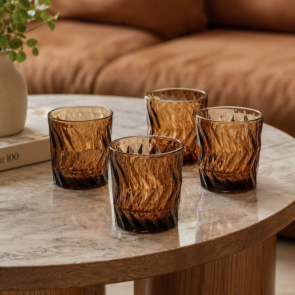 Jackson Drinking Glasses set of four in rich amber patterned glass, styled on a warm dining table with layered tableware and decorative accessories.
