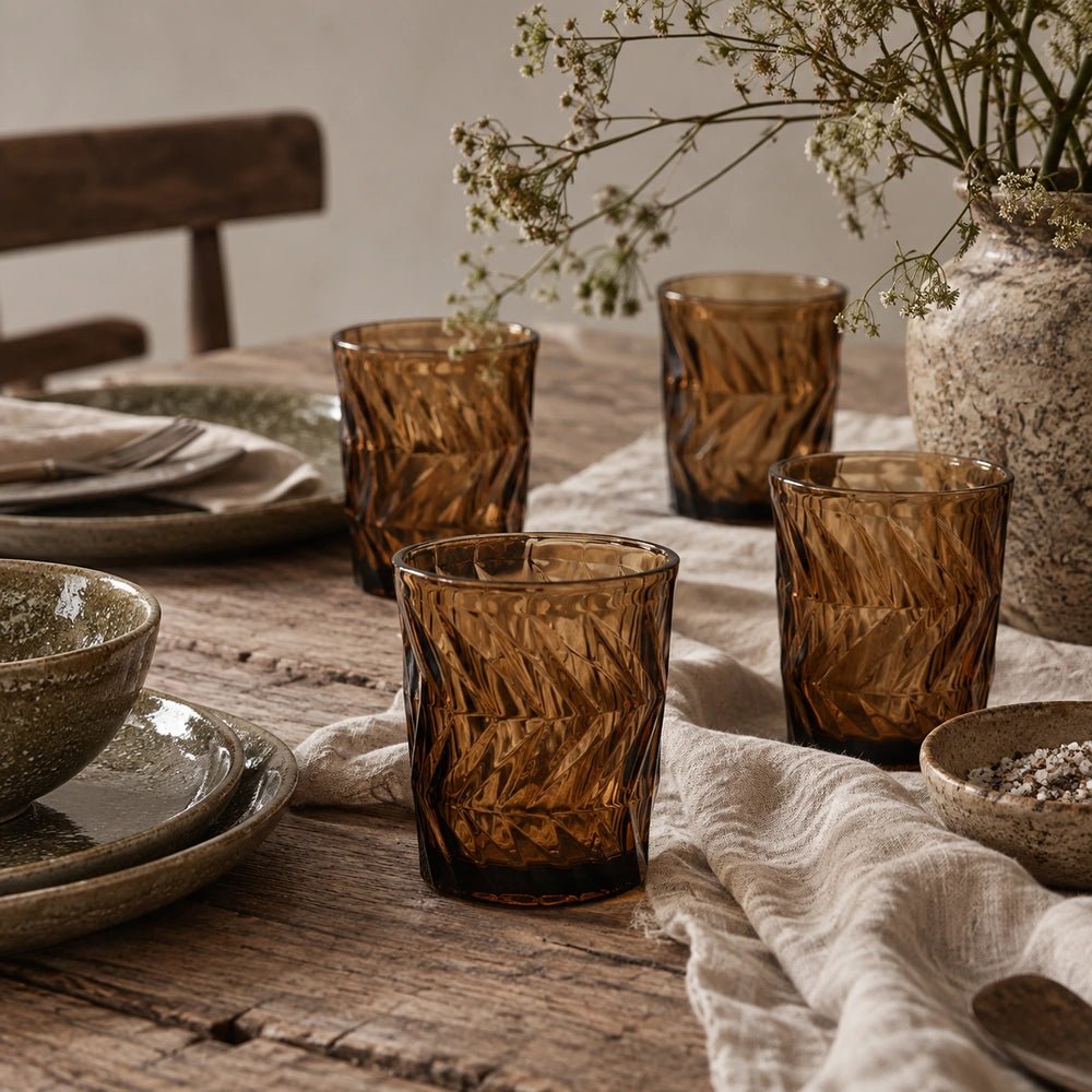 Jackson Drinking Glasses set of four in rich amber patterned glass, styled together on a warm table with layered neutral dining accessories.