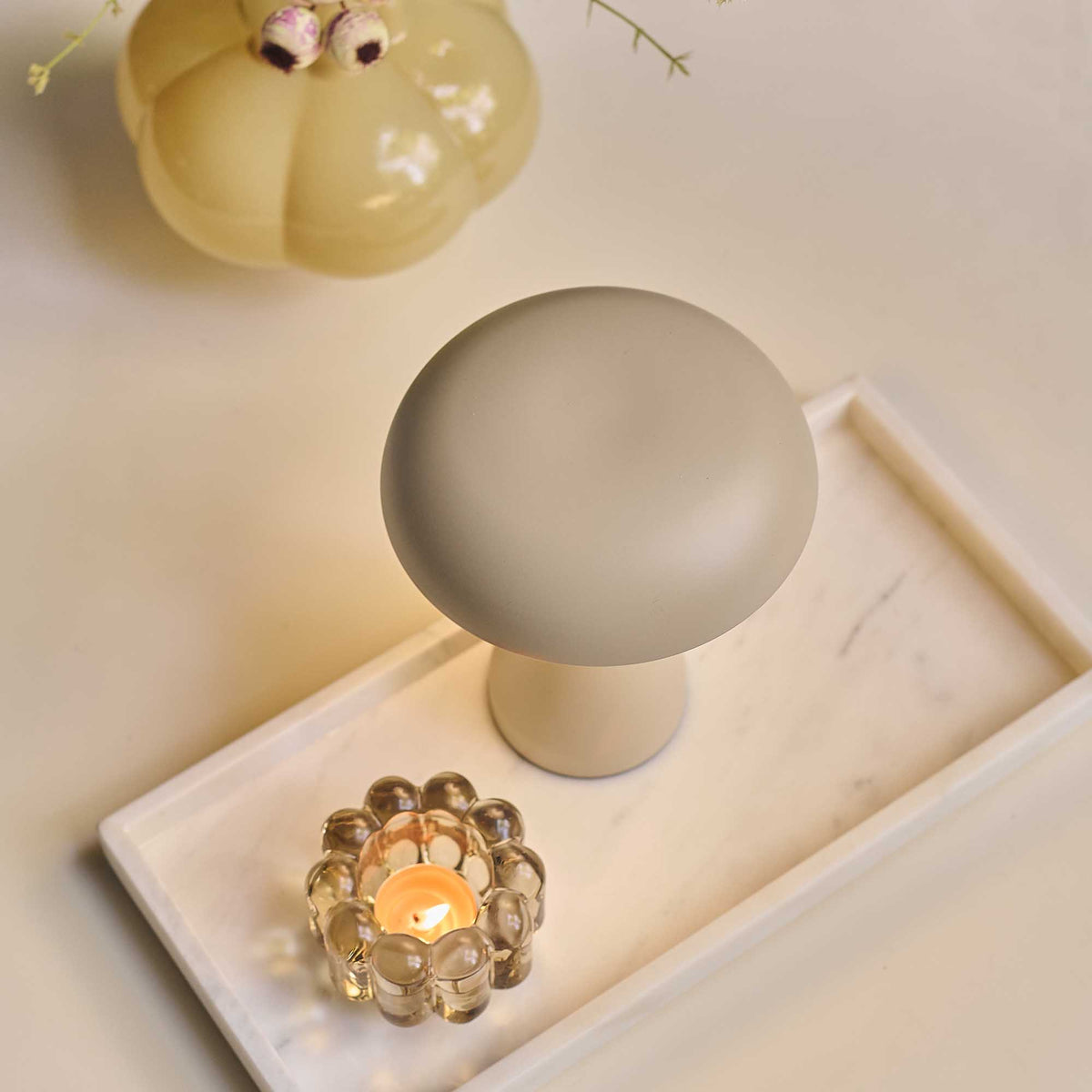 Small dome portable lamp on a marble surface with a lit candle below