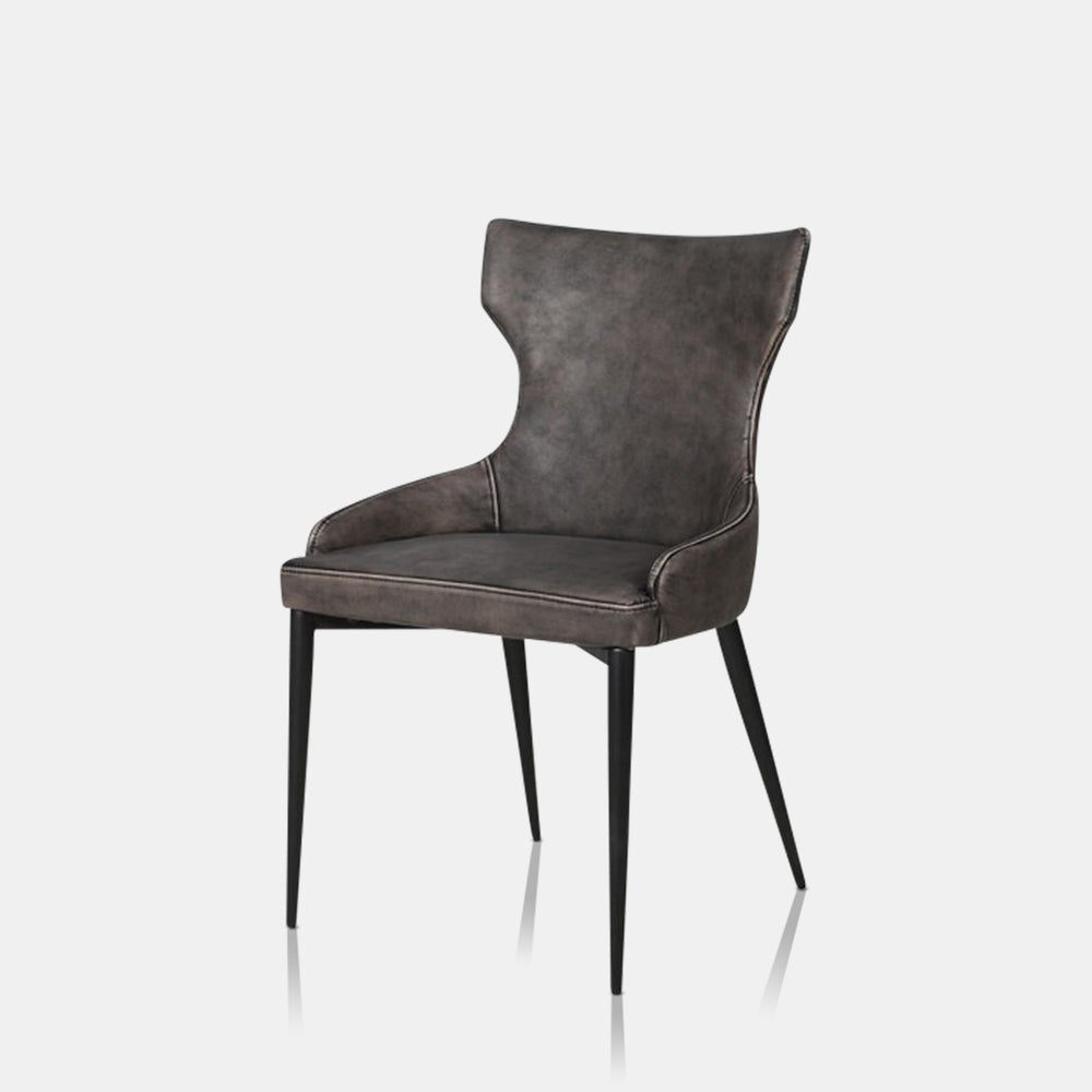 A cutout of the Lawler Grey Dining Chair, a soft grey faux leather chair with a curved back and a vintage feel.