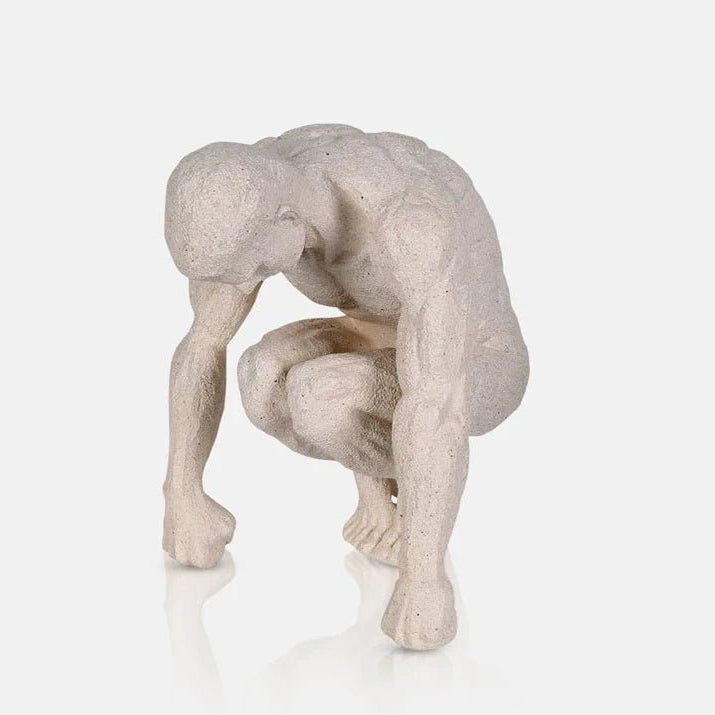 Lawrence Figurative Sculpture depicts a pale seated figure with a bowed head, bent knees and elongated arms, finished with a softly textured sculptural surface.