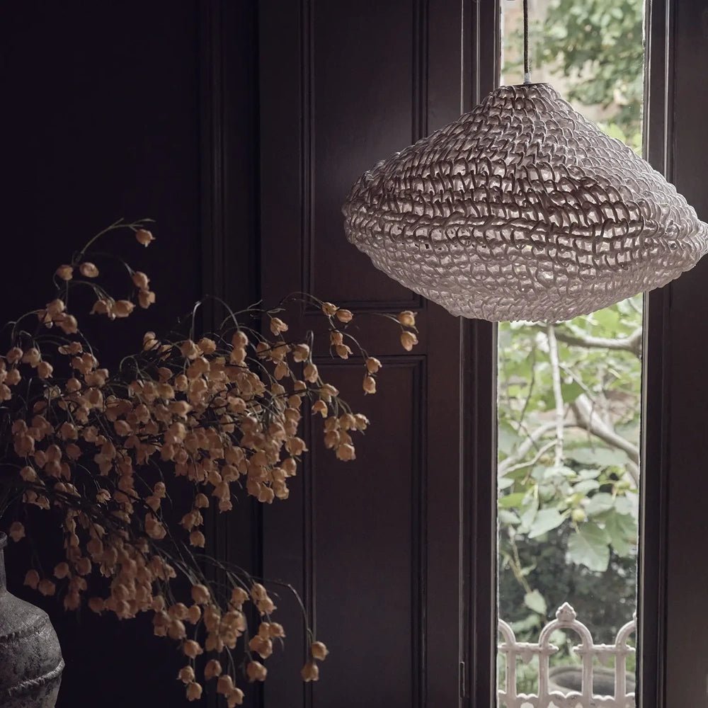 Livington Paper Rope Pendant has a broad woven cream shade suspended beside a tall window, with dried flowers and dark panelling in the background.