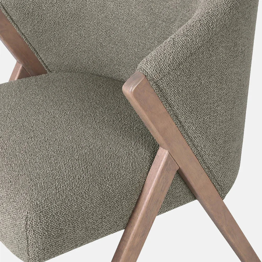 Lyndon Curved Accent Chair in pistachio shows green textured upholstery meeting an angled wooden frame, highlighting the padded seat and rounded back in close-up.