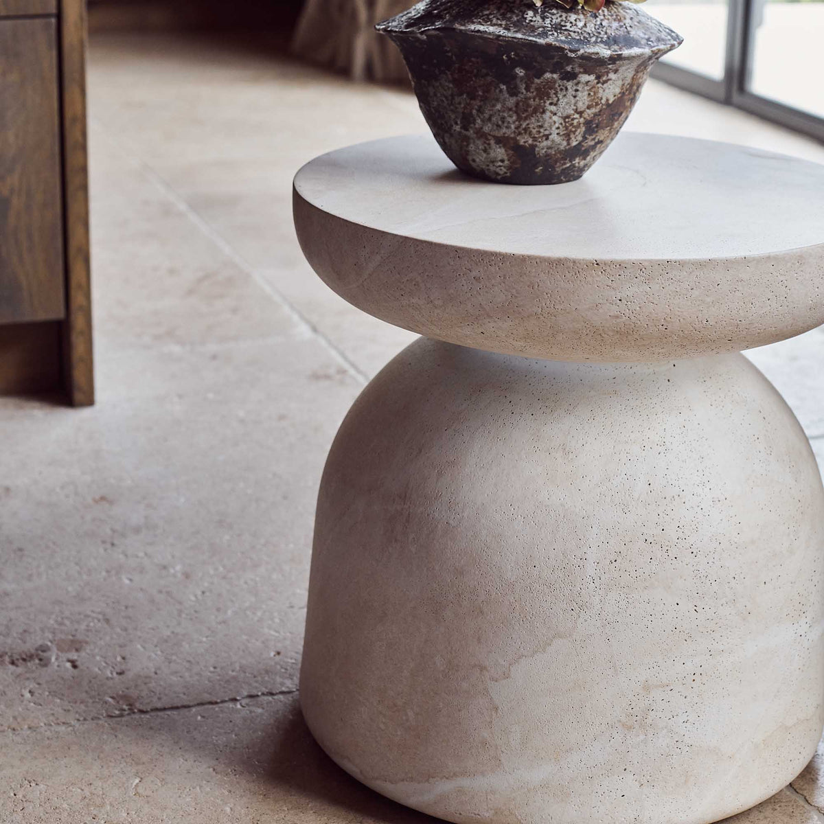 Modern and sculptural, the smooth stone effect Diablo side table in neutral tones, with smooth curved edges & elegant rounded profile perfect as a base to show off a beautiful sculpture or a vase of flowers, perfect for any indoor or outdoor living situation 