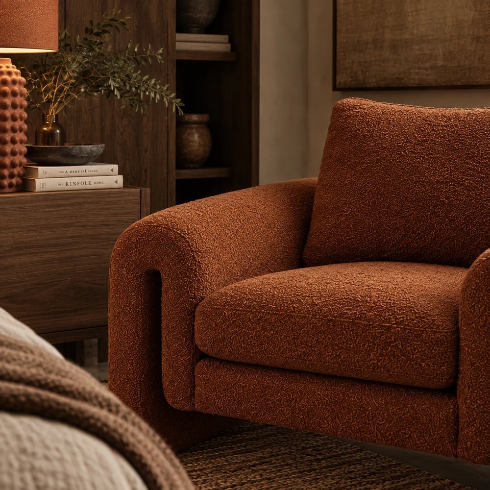 Manhattan Boucle Armchair in rich rust textured boucle, styled in a warm interior corner with layered neutral accessories and contemporary furnishings.