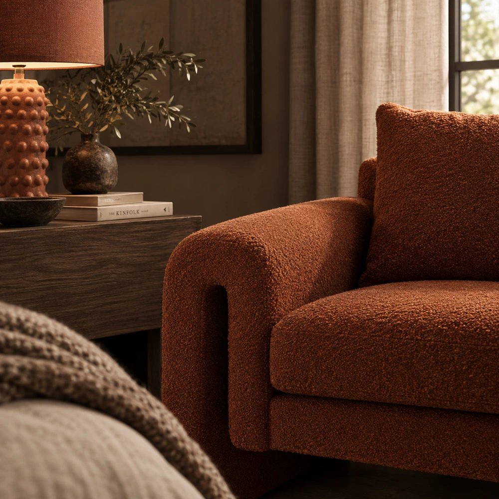 Manhattan Boucle Armchair in rust boucle fabric, styled in a layered contemporary room with warm neutral textures, sculptural furniture and decorative objects.