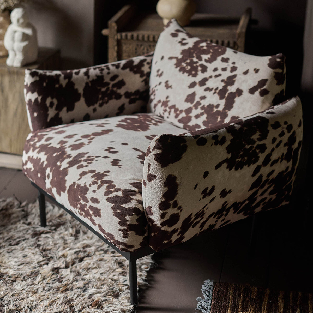 Brown and white cowhide print armchair with a structured silhouette, plush upholstered seat and bold statement pattern. Melvin Armchair by Abigail Ahern, designed to bring a stylish focal point to modern living rooms, bedrooms, dining spaces and eclectic interiors. A luxury accent chair combining comfort and contemporary design, perfect for adding character, texture and designer style to your home decor.