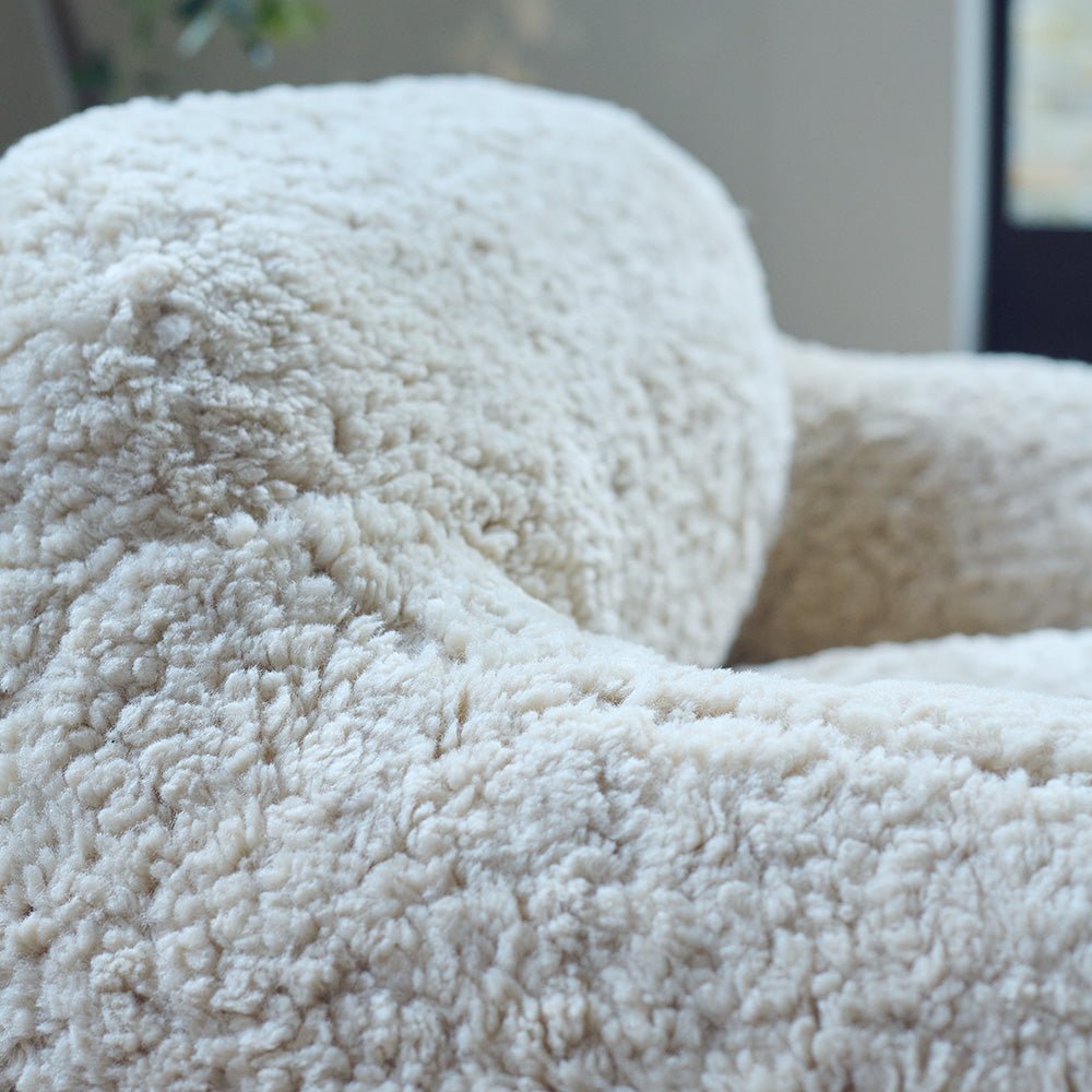 A closeup of the soft cream faux shearling upholstery on the Monroe Faux Shearling Armchair.