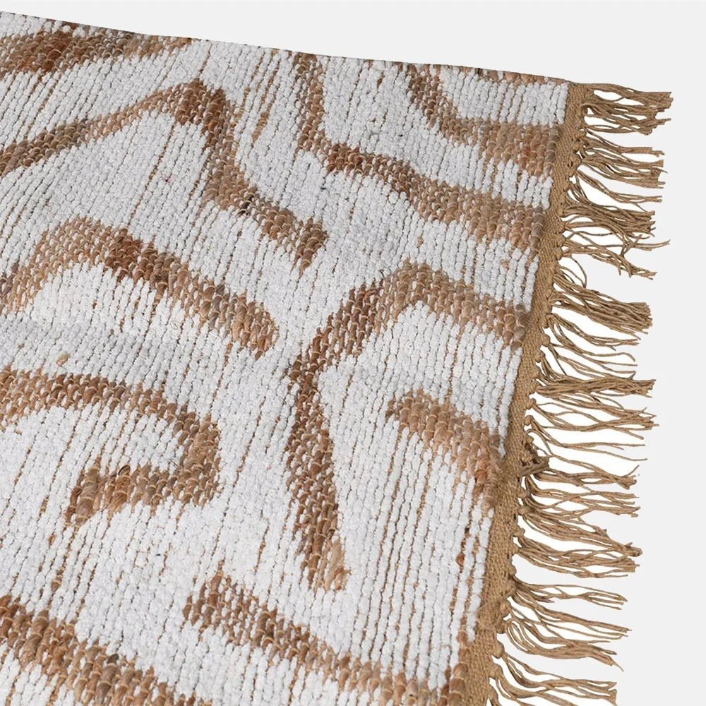 Montgomery Chenille Jute Rug shows its cream and tan abstract pattern beside a fringed edge, highlighting the woven texture and contrasting curved lines in close-up.