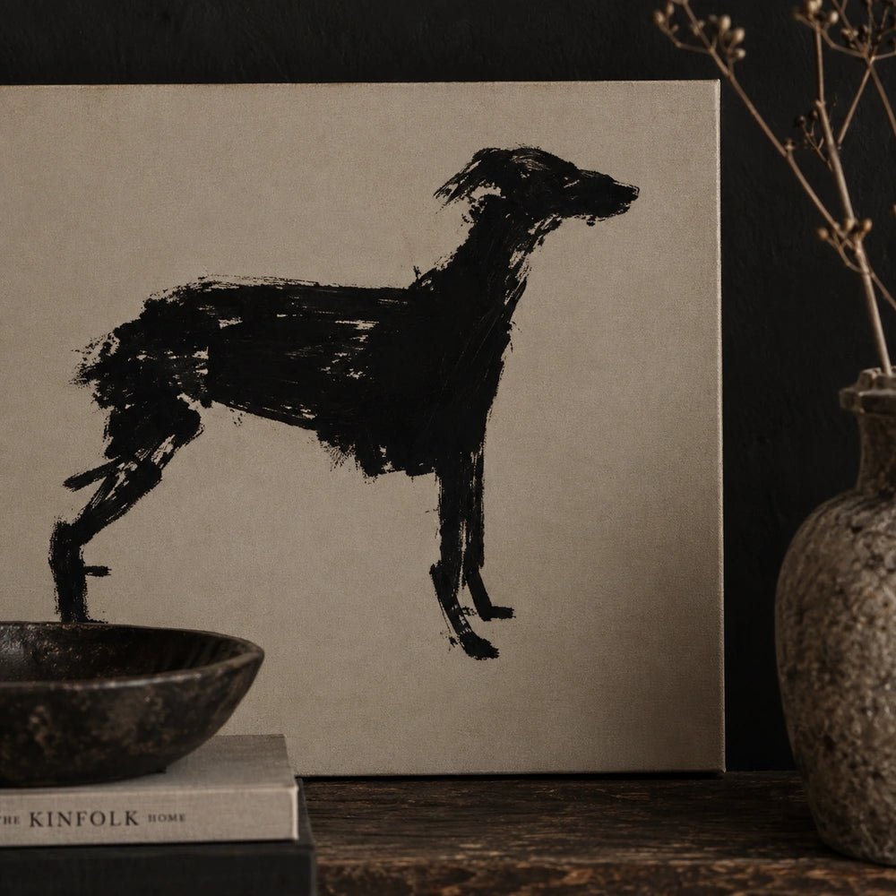 Murphy Dog Print featuring a bold black brushstroke dog silhouette, displayed on a dark console beside stacked books, bowls and a textured vase.