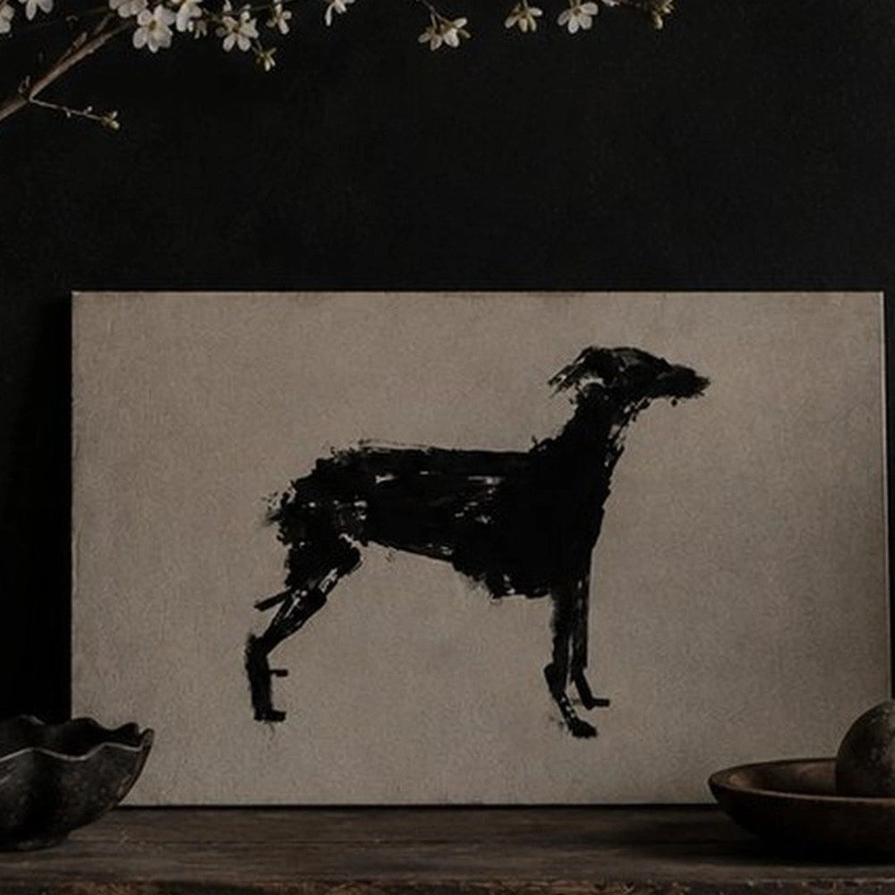 Murphy Dog Print displayed above a dark sofa, featuring a black brushstroke dog silhouette in a warm living room with neutral cushions and lighting.