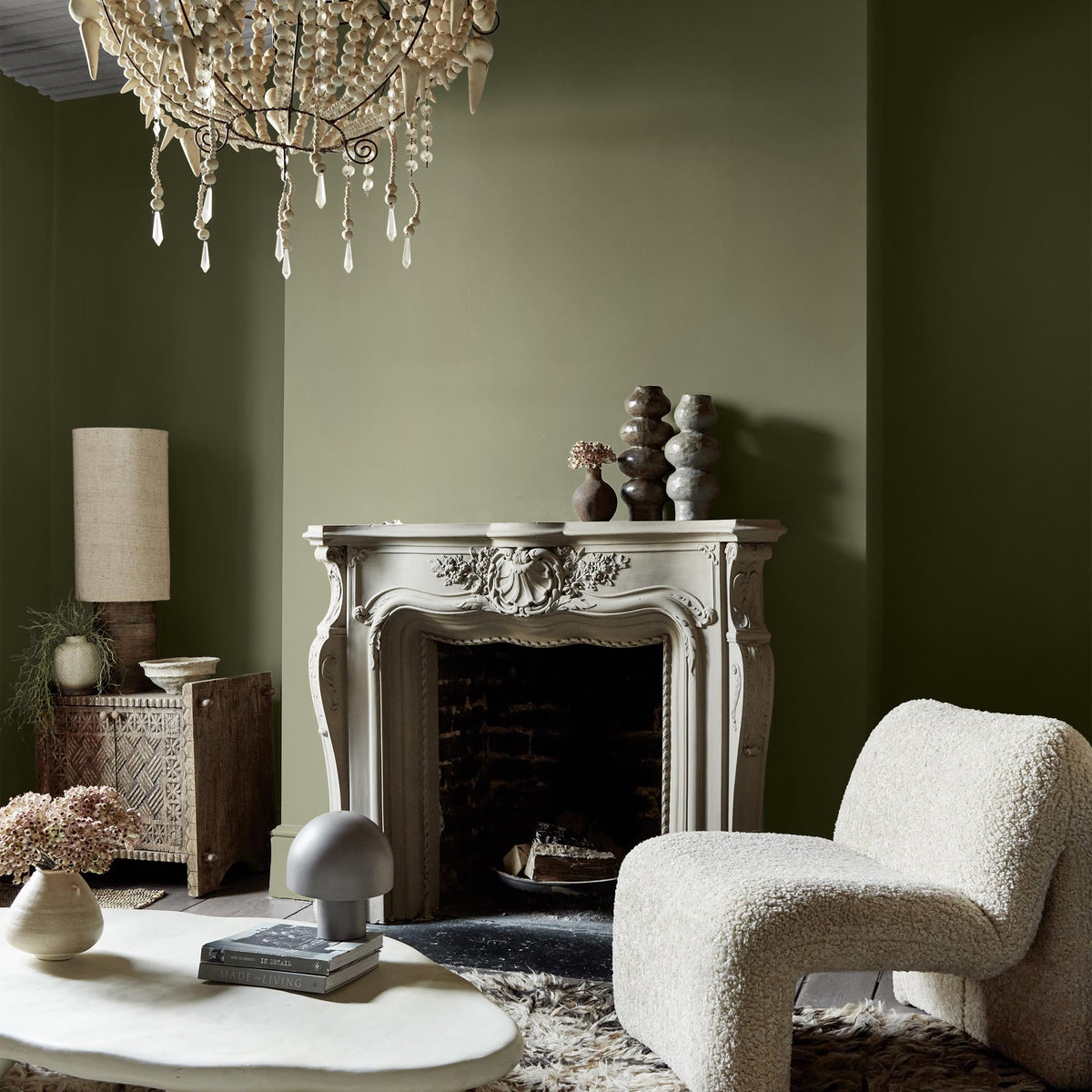 Abigail Ahern Neptune Grass paint – a sumptuous dark sage green enveloping a beautifully styled living room with fireplace, coffee table and accent chair