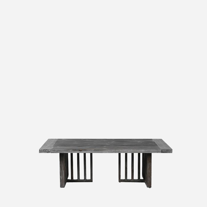 The Newton Grey Wood Coffee Table, a low rectangular table in dark fir wood with a limewash effect and fence-like legs.