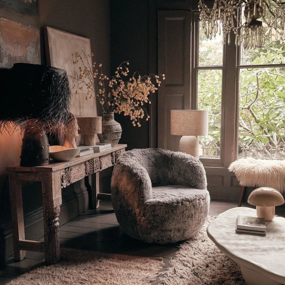 Norwood Sheepskin Swivel Chair combines a rounded seat and curved arms with grey textured upholstery, styled beside a console, table lamp and circular coffee table.