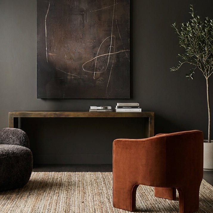 Abigail Ahern Burnished Gold Iron Console Table styled against a wall in a contemporary hallway, providing an elegant surface for lamps, books and decorative accessories.
