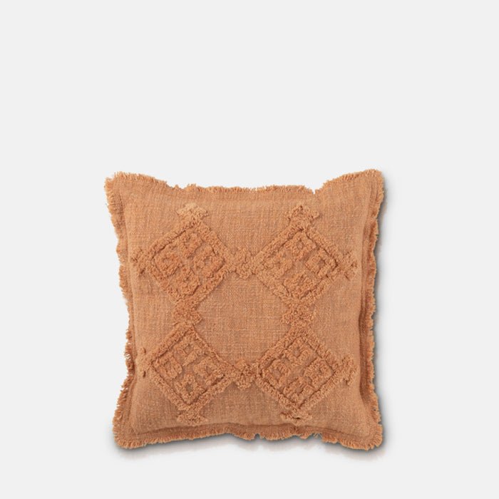 Cutout of the Pamra Cushion, a square cotton cushion in a soft rust colour with a tufted geomtric pattern and a short fringe.