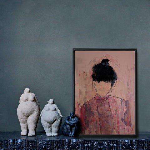 Pink female figure in a thin black frame leant on a wall next to three female sculptures