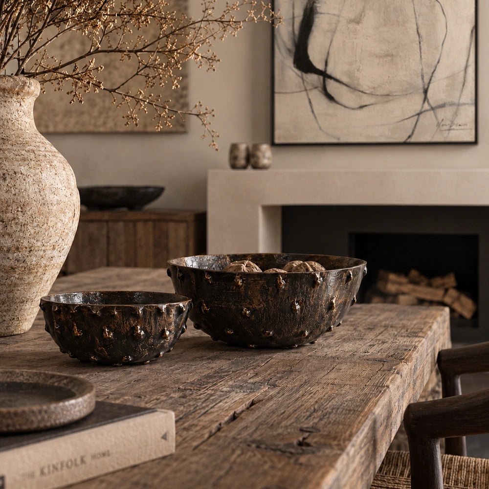 Portrush Metal Bowls set of two styled on a dark wooden console with sculptural vessels, warm lighting and layered neutral decorative accessories.