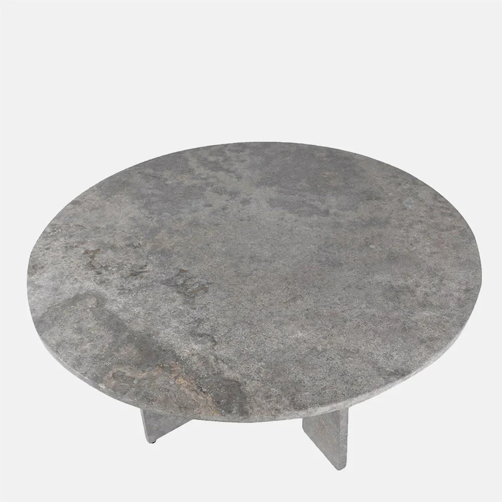 Randolph travertine dining table viewed from above, showing its round grey mottled top and the angular supports visible beneath the softly rounded tabletop edge.