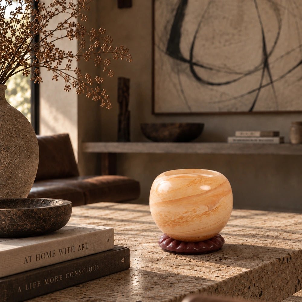 Ravello Glass Candle Holder, Peach with sculptural translucent glass form, styled on a pale stone table beside stacked books and warm neutral interior furnishings.