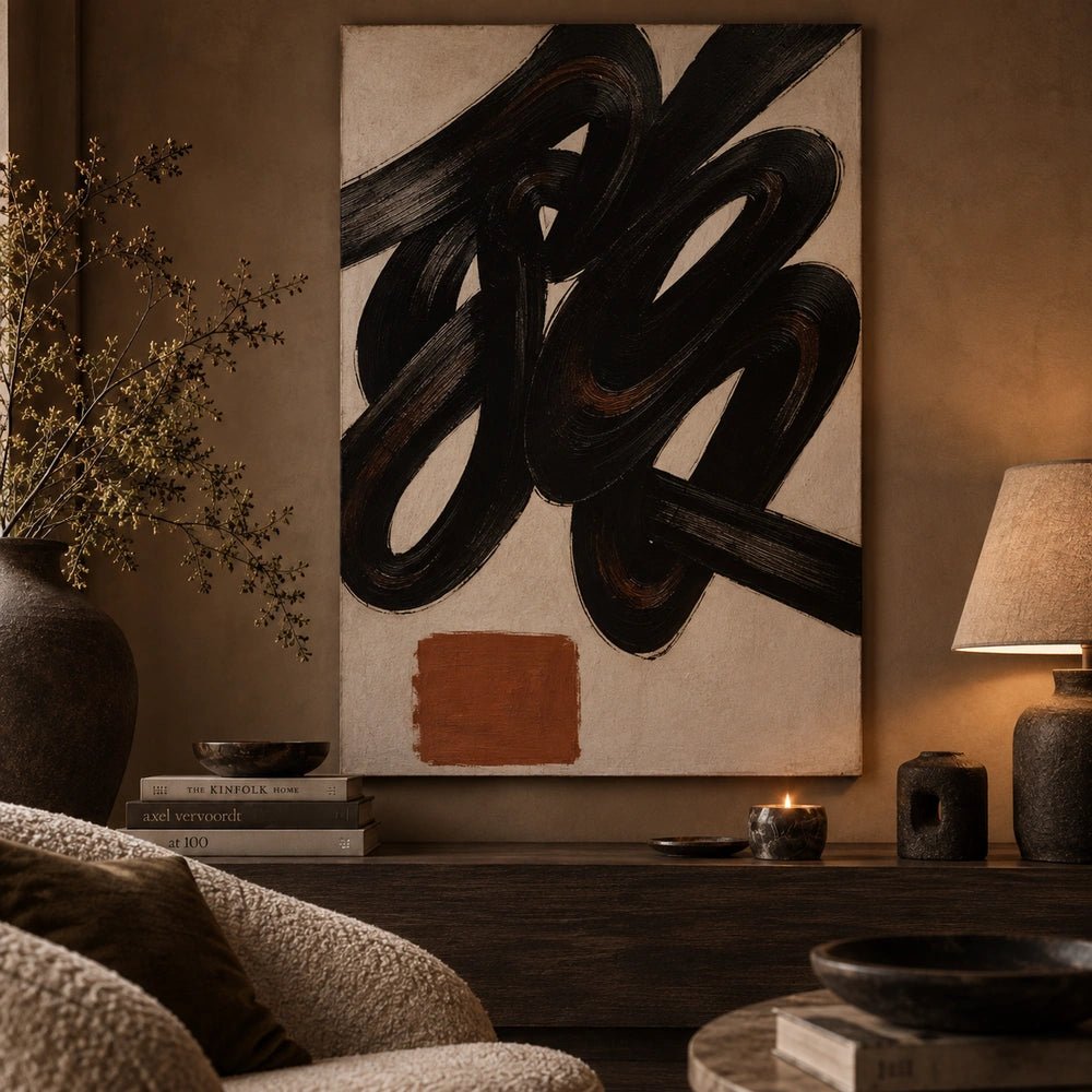Romer Abstract Canvas displayed above a dark sofa in a moody living room, with bold black swirling artwork, neutral cushions and sculptural accessories.